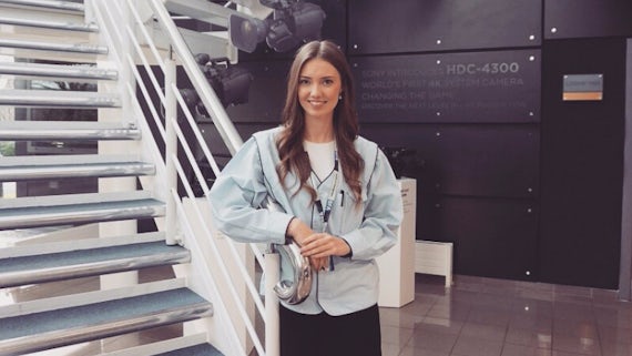 Image of Hannah Williams, young woman wearing a blue shirt, standing near a staircase