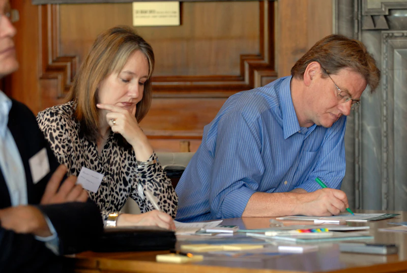 Man and woman sitting at a table, writing