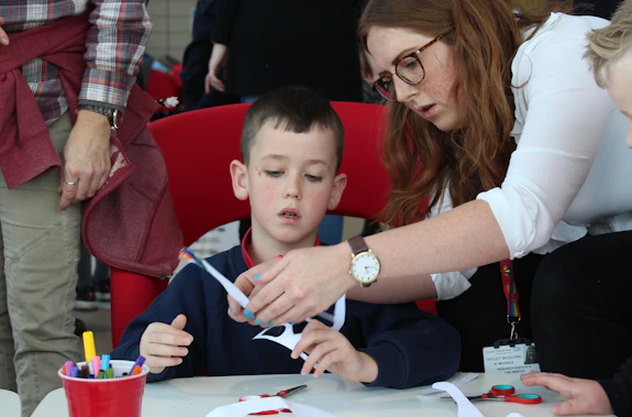 Child and researcher cutting out glasses