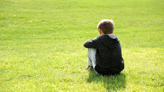 Image of a child sat alone in a field