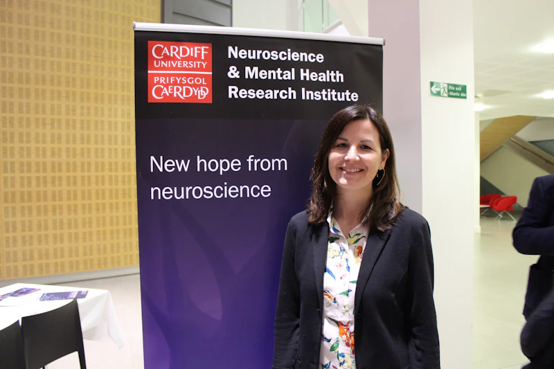 Photograph of Staci Bilbo in front of a banner