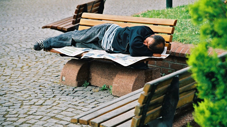 Image of homeless man sleeping on a bench