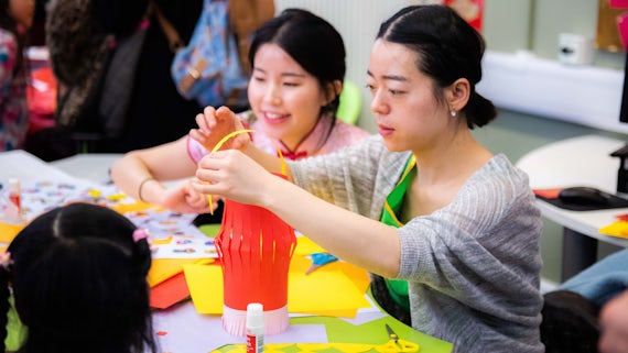 Chinese tutors help children to make Chinese lanterns