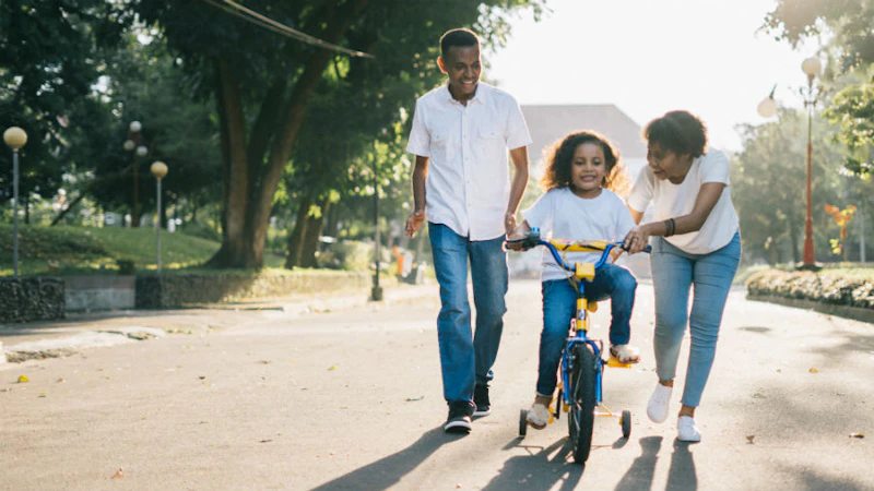 Child learning to ride a bike with her parents