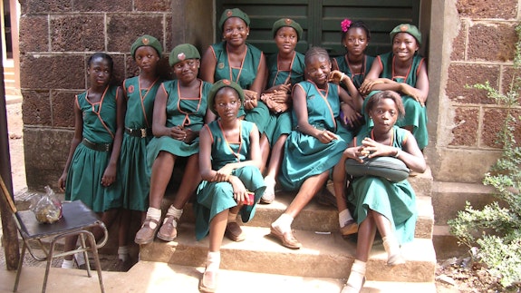 Group of school girls in uniform sitting on steps in Sierra Leone