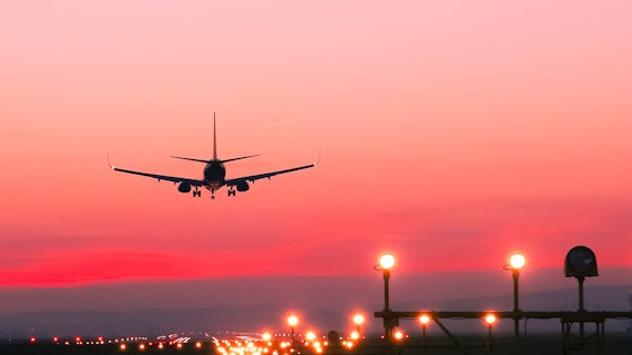Stock image of plane flying into the sunset