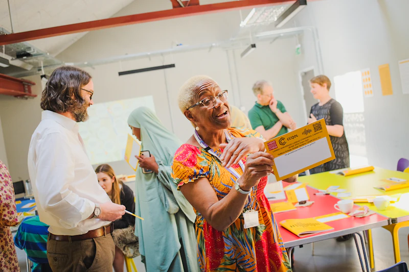 A woman in glasses is discussing the findings of the Community Voices Cardiff report.