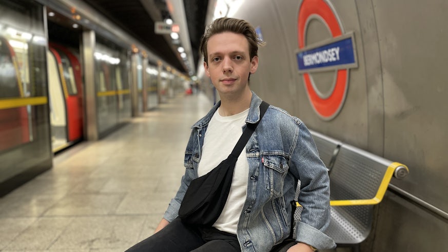 A male wheelchair user poses for a photograph beside a train at the Bermondsey London Underground station.