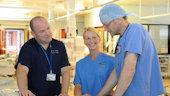 Three staff members wearing scrubs in a hospital setting