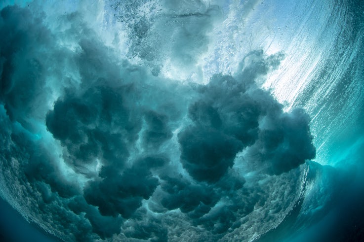 A powerful wave crashing down is photographed from beneath