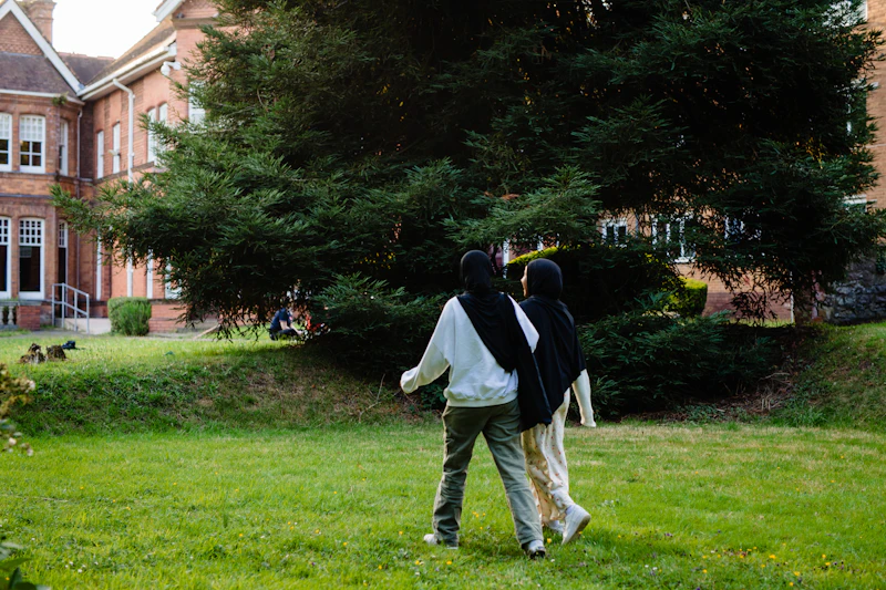 Two students walking through green campus grounds during the Step Up summer school.