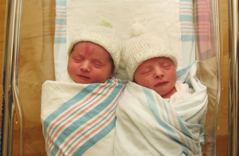 Two twins lying in hospital cot together