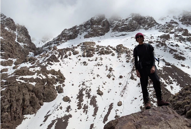 Zara Siddique hiking a snowy mountain wearing a climbing helmet