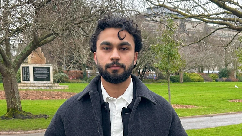 Noor Ullah Khan - a man stood outside on the grass wearing a black coat.