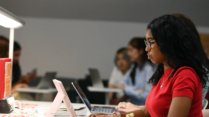 Girl in red top sat at a desk using a laptop