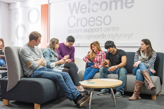 Students at a desk with a welcome sign in the background