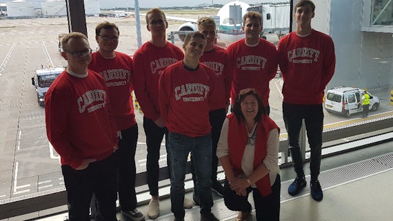 Image of seven male students and Dr Jane Lynch at Heathrow Airport 