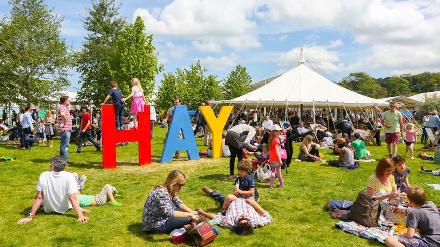Image of a busy Hay Festival field, with HAY in large free standing letters.
