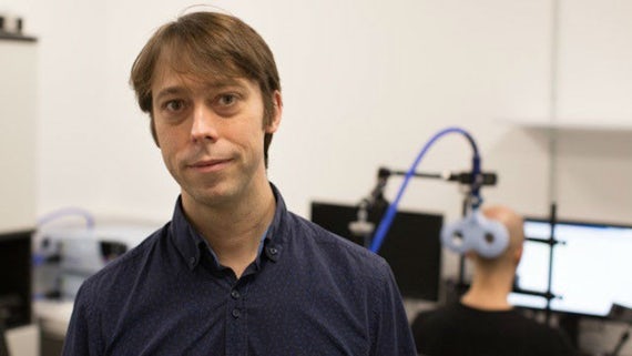 Picture of a CUBRIC research fellow with a blurred background of a participant receiving brain stimulation