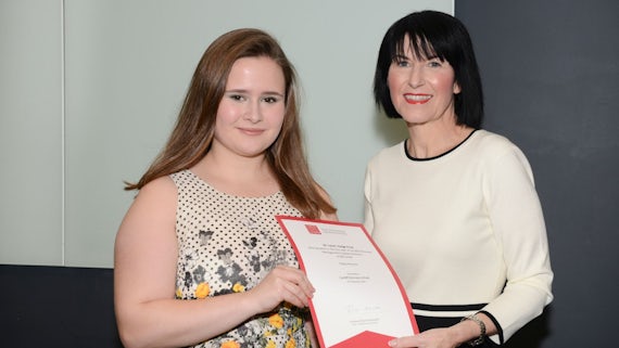 Female student collects award from Dean