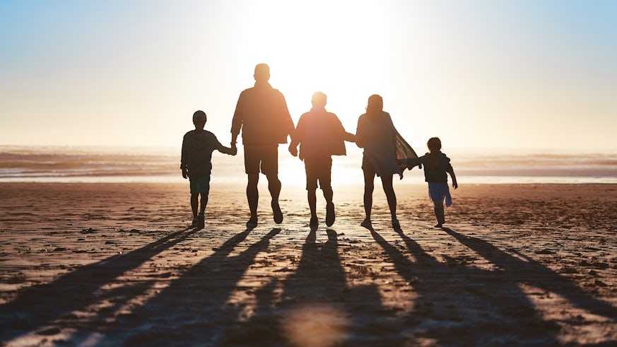 Family on beach silhouetted against sunrise