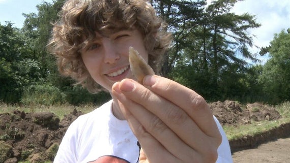 Young man showing a find from archaeological dig.