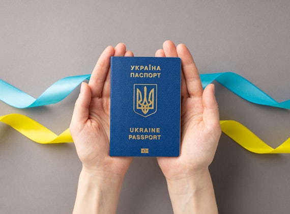 Two hands holding a Ukraine passport