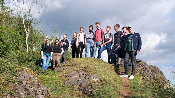 A number of students standing on a rocky outcrop.