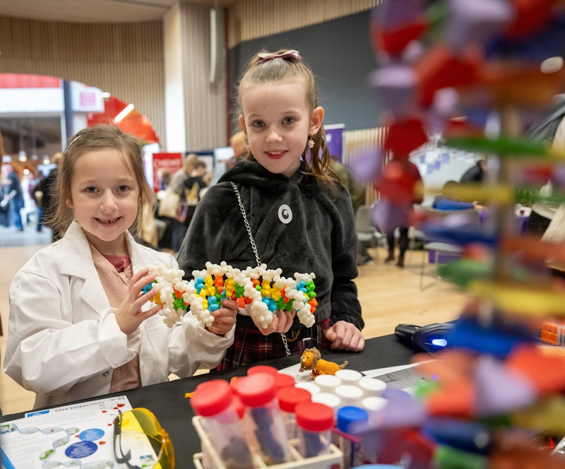 Two young girls hold a DNA model.