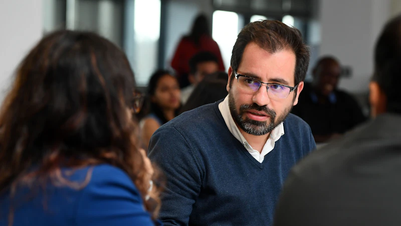 A male MBA student in discussion with fellow students.