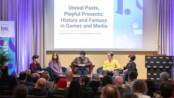 A five-person panel addressing an audience at a conference