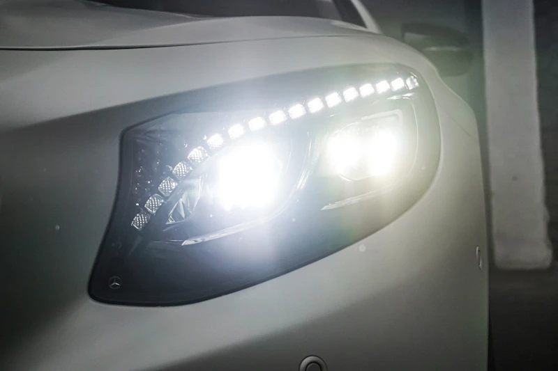 A close up photograph of the left hand headlights of a white car