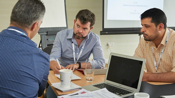 Three men in a meeting.