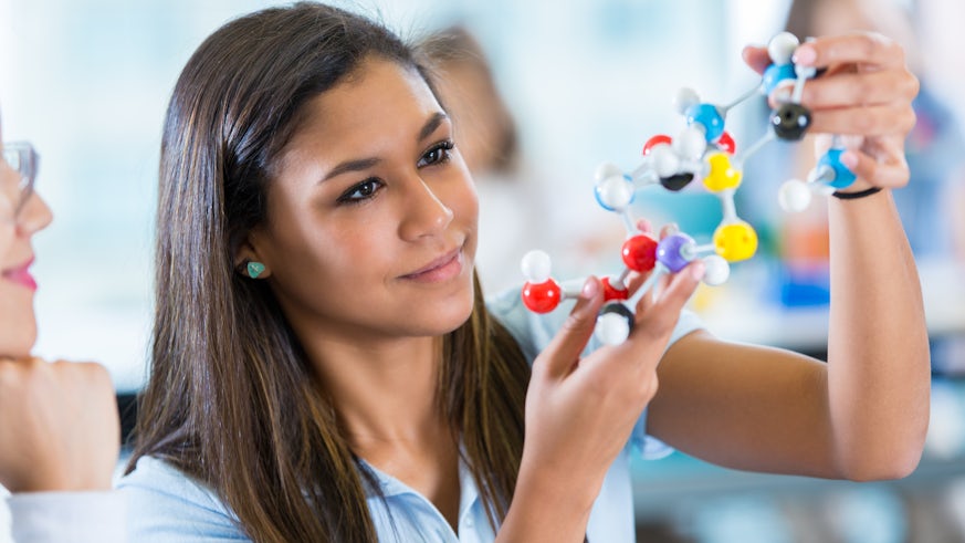 Female student using molecule models in science class