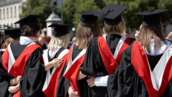 Back view of students in gowns linking arms