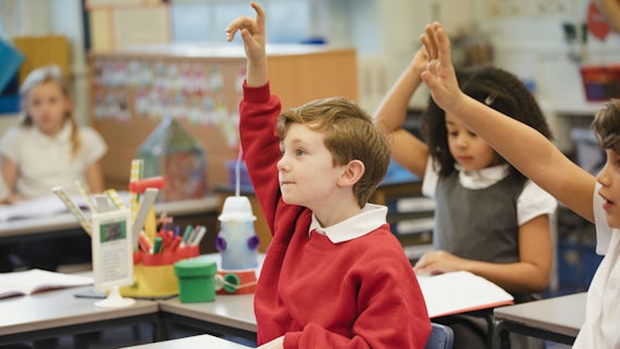 Primary school pupils with hands in the air
