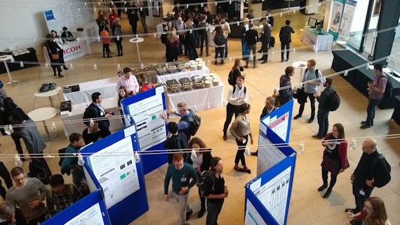 MEG researchers look at poster presentations in an atrium