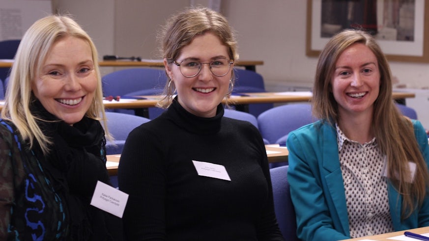 Image of three PhD students in a lecture theatre 