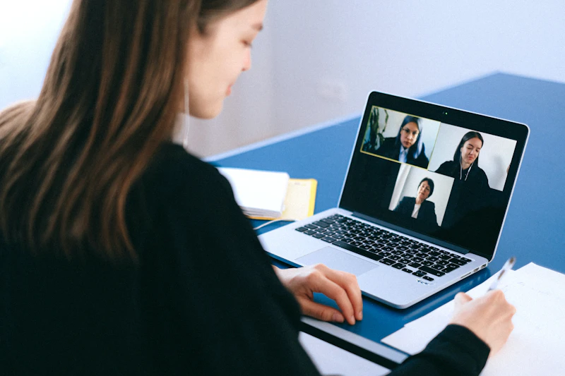 A diverse group of young people sit on steps viewing a laptop