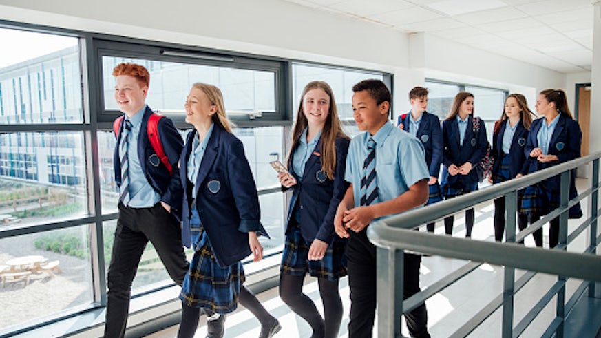 Pupils walk in school uniform in a corridor