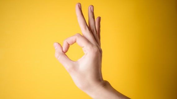 Hand showing ok symbol against yellow background
