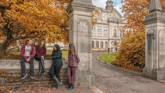 Four students outside Main Building in Autumn