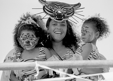 Black and white photograph of a woman holding two children, they are all dressed up as tigers