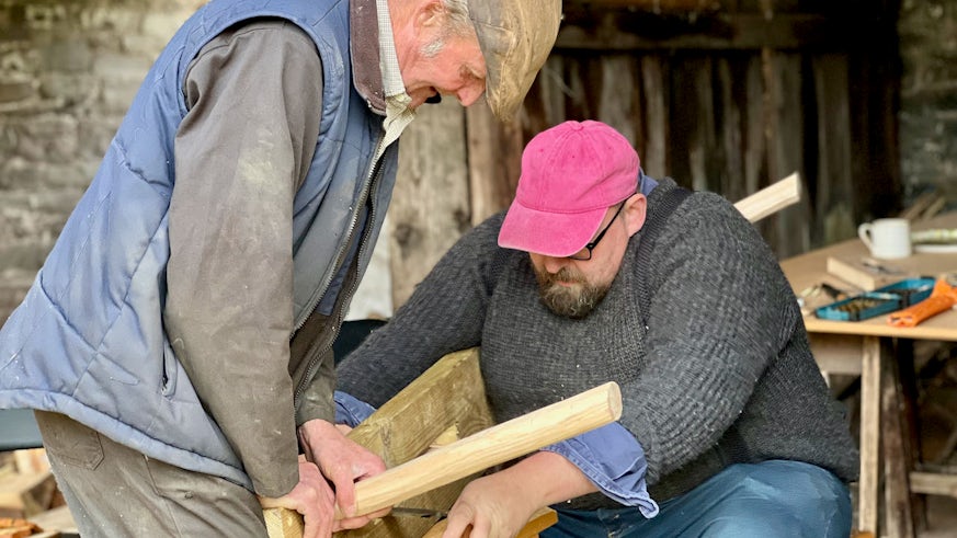 Two men working together to build a wooden stool