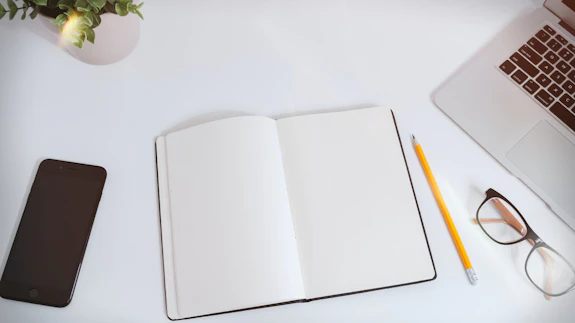 White work table with notes, smartphone and laptop