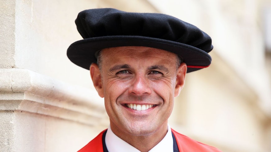 A head and shoulders photograph of Jason Mohammad in a graduation cap and gown