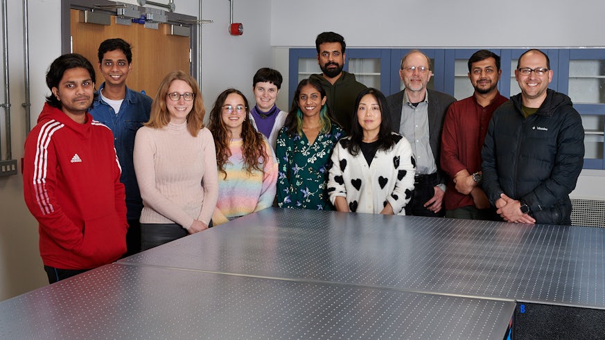 Staff and students pose for a photograph around a table in a new laboratory facility