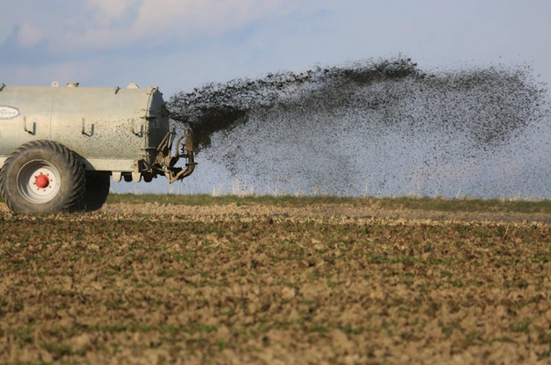 A truck spreading sewage onto a field