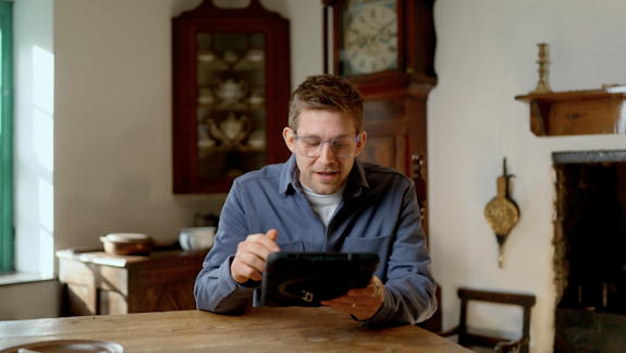 A photograph of Steffan Powell in a period building with an iPad
