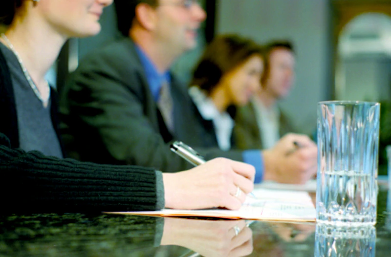 Four people sitting at a table with pens in their hands.